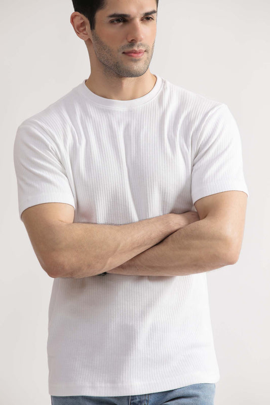 A man wearing a white knit drop needle tee shirt with short sleeves, paired with light blue jeans.